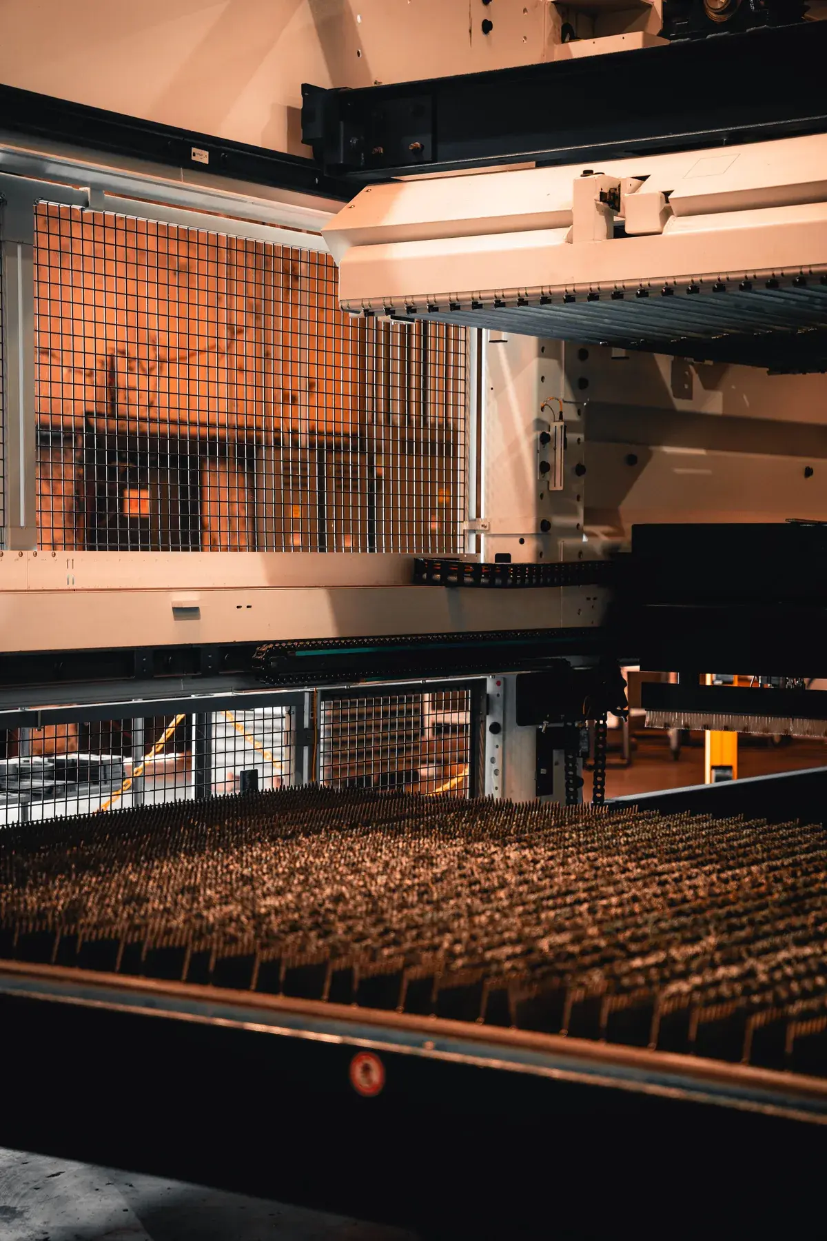 Slatted flat-sheet laser cutting bed beneath the machine's material-handling equipment.