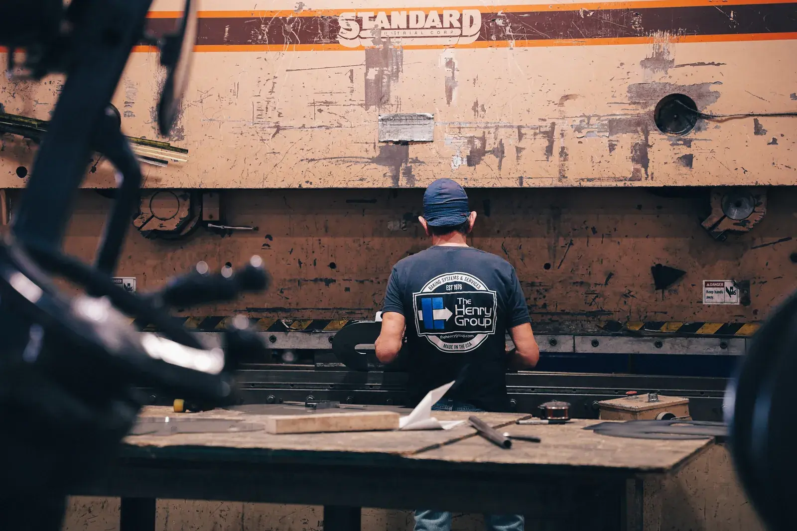 Operator in a Henry Group shirt working at an orange press brake.