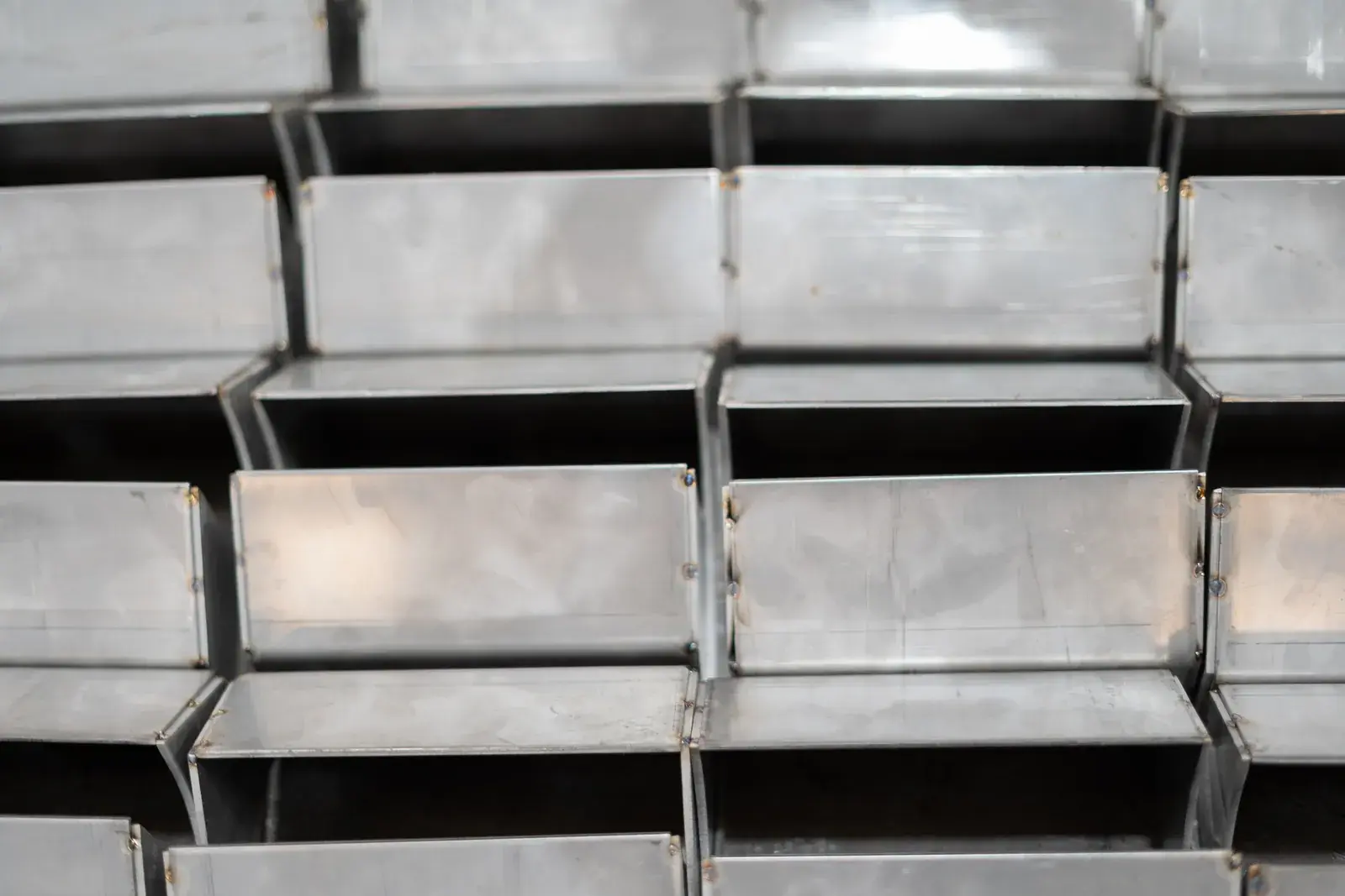 Rows of formed sheet metal assemblies with repeated bends and joined edges.