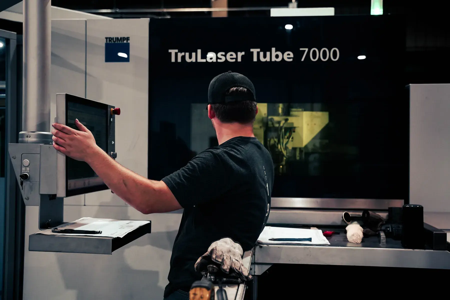 Operator at the controls of a TRUMPF TruLaser Tube 7000, with the machine name visible above the enclosure.