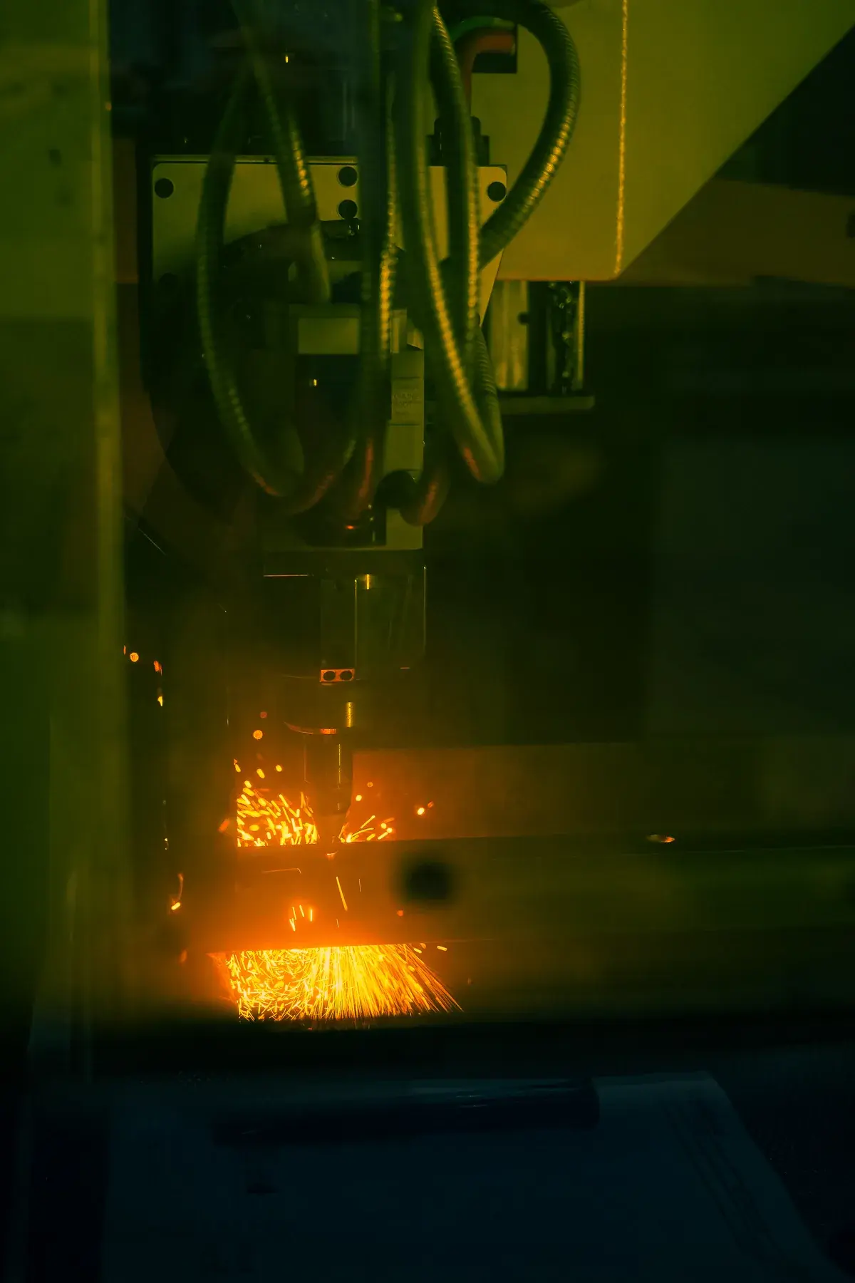 Laser cutting a rectangular tube, with sparks visible through the yellow protective window.