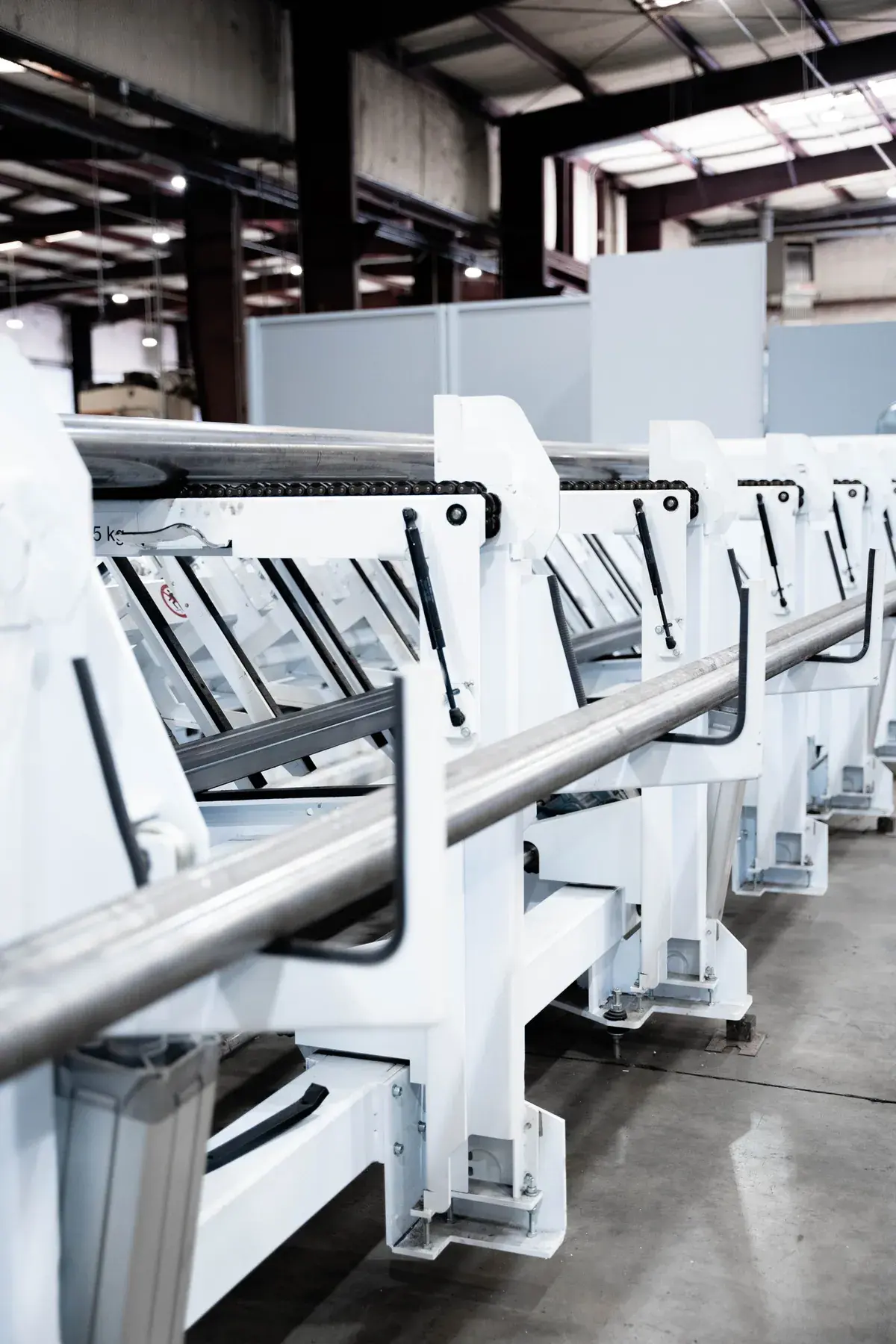 Round metal tube positioned in the tube laser's white material handling supports.